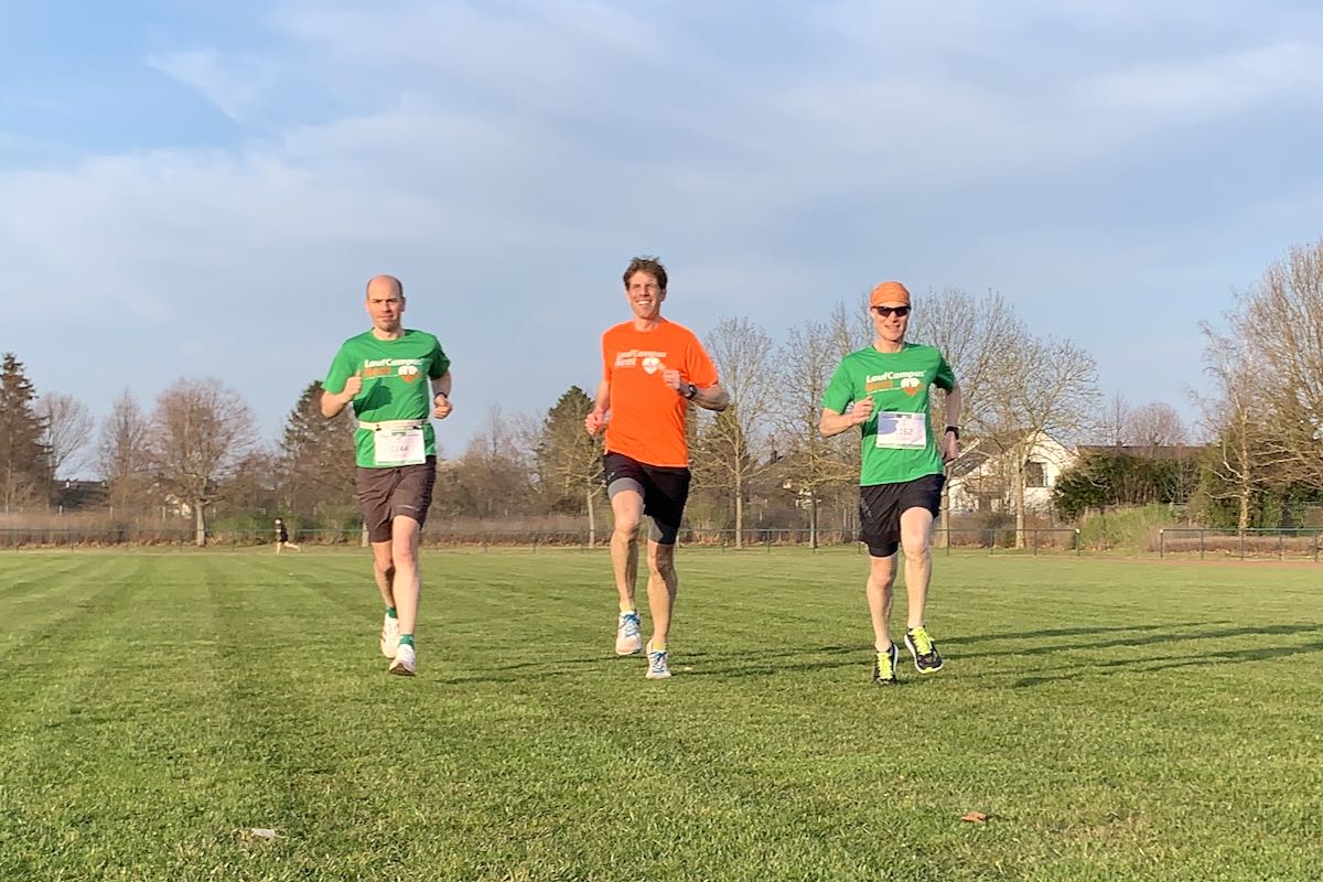 Drei Läufer mit Startnummer beim Training für einen virtuellen Marathon